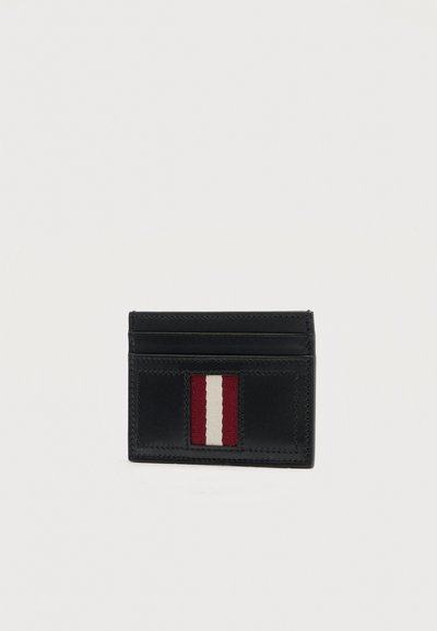 Porte-cartes en cuir noir avec deux emplacements pour cartes et une poche avant ornée d'un détail en tissu rayé vertical rouge et blanc.