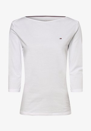 Biała dopasowana koszula z długim rękawem, z dekoltem typu łódka i małym logo flagi Tommy Hilfiger na lewej piersi.