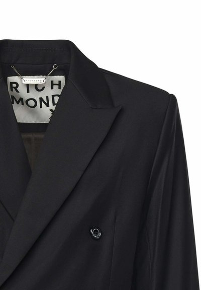 Blazer negro de tela suave con una silueta estructurada, solapas de muesca y un detalle de un solo botón negro. Incluye una etiqueta de marca en el interior.