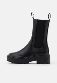 Black ankle boot with a smooth leather finish, elastic side panels, pull tabs, and a thick, textured sole for added grip.