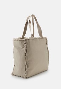 Beige Tragetasche mit ausgefranstem Rand, aus strukturiertem Stoff gefertigt. Verfügt über kontrastierende glatte Träger. Quadratische Form und mittlere Größe.