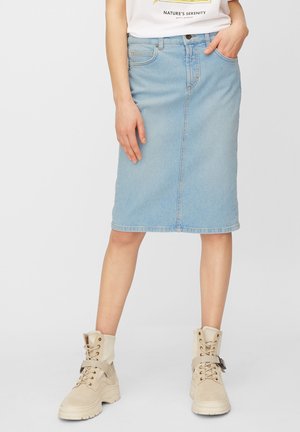 Jupe midi en jean bleu clair avec une coupe droite, design classique à cinq poches et coutures apparentes. Portée avec des bottines beige à lacets.