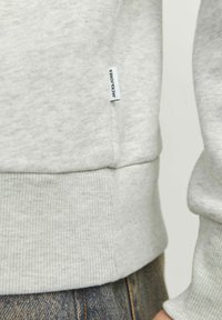 Hellgrauer Sweatshirt aus Baumwollmischung. Verfügt über gerippte Bündchen und Saum, eine dezente Textur und ein kleines "Jack & Jones"-Schild an der Seite.