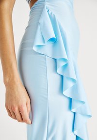 Robe ajustée bleu clair avec un détail de volants sur le côté, fabriquée dans un tissu lisse. Présente une silhouette épurée et une couture délicate.