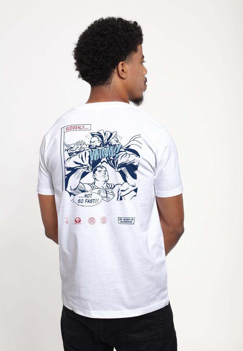 Hvid bomulds t-shirt med et blåt comic-style print på ryggen, der viser actionbilleder og teksten "PLUDSELIGT... IKKE SÅ HURTIGT!!"