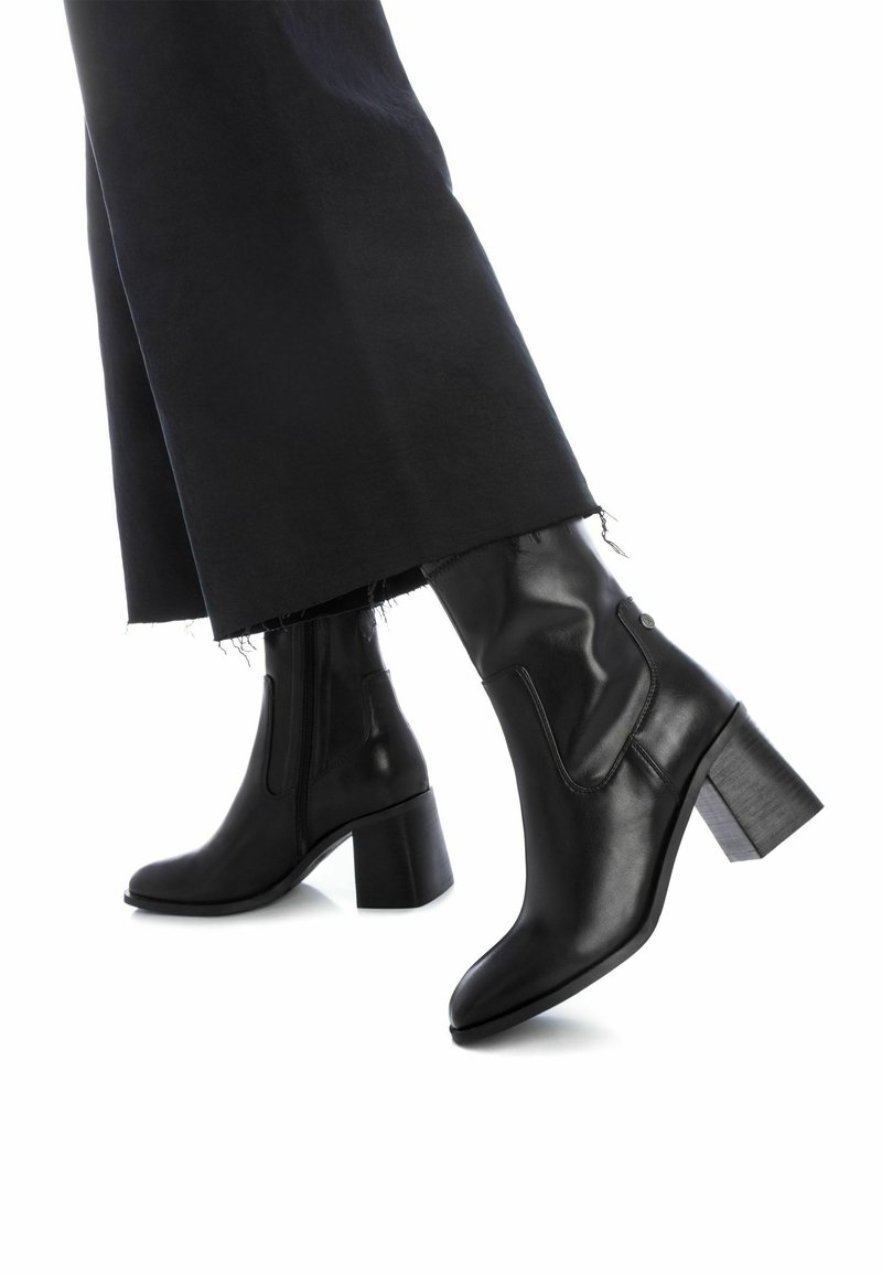 Botas de cuero negras hasta el tobillo con punta cuadrada y tacón de bloque, con cierre lateral y detalles de costura minimalistas.