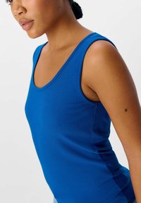 Top sin mangas de canalé azul con escote redondeado y tirantes anchos, que presenta una textura suave y un diseño ajustado al cuerpo.