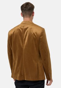 Blazer de terciopelo marrón con una textura suave, abertura trasera sencilla y cuatro botones en cada puño. Ajuste entallado con un diseño de solapa muesca.