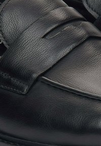 Czarne skórzane buty o gładkiej fakturze, z szerokim paskiem zapinanym na szwy dla wsparcia i komfortu.