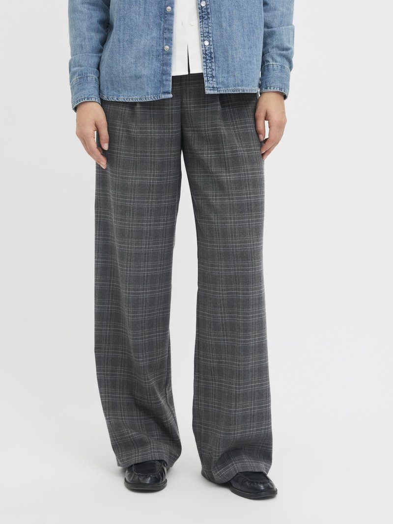 Bredde ben rutete bukser i grått og svart med en myk tekstur. Kombinert med en denimskjorte og svarte slip-on sko.