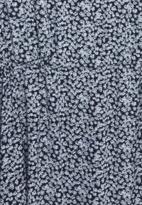 Květinové šaty s námořnickým pozadím a bílými květinovými vzory, lehký materiál, délka ke kolenům a stažený pas.