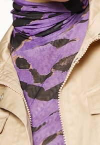 Purple and black patterned scarf with a soft texture, layered under a beige zip-up jacket. Notable stitching and zipper details visible.