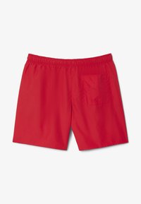 Shorts de bain rouges avec une taille élastique et une poche arrière unique, fabriqués à partir d'un matériau lisse et léger. Design simple, de couleur uni.