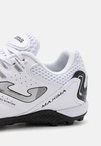 Białe syntetyczne buty sportowe z siateczkowymi akcentami, czarną podeszwą, fakturowanym obcasem oraz srebrnymi detalami. Posiadają sznurowane zapięcie i logo.