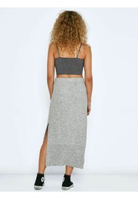 Jupe maxi en maille grise avec une fente latérale, portée avec un crop top gris ajusté et des baskets noires, présentant un tissu texturé et un design décontracté.