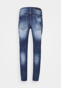 Kapeat farkut tummansinisestä denimistä, jossa on haalistumista ja kulutettuja yksityiskohtia. Sisältää taskut, vyölenkit ja brodeeratun logon vyötäröllä.