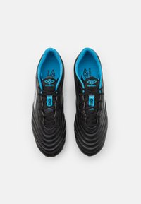 Scarpe da calcio in pelle nera con design testurizzato, dettagli bianchi e solette blu. Presentano una chiusura con lacci standard e punta rotonda.