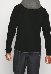 Black jacket with a gray hood, sleek design, textured fabric, and elastic hems. Features include a side pocket and contrasting stitching.