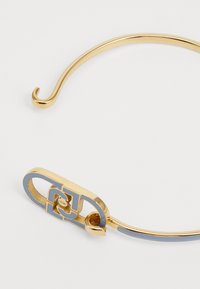 Gouden haarspeld met een gebogen, slank ontwerp. Voorzien van een geometrisch patroon in blauwe emaille bij de sluiting, met een haak aan het ene uiteinde voor een veilige bevestiging.