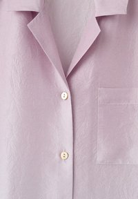 Chemise violet clair avec une texture légèrement froissée, un col, deux boutons beige et une poche poitrine carrée sur le côté droit.