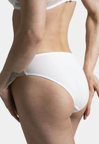 Culotte en coton blanc avec une texture douce, une taille élastique et des bords sans couture, montrant un gros plan de l'arrière et du profil latéral.
