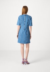 Denimmekko lyhyillä hihoilla, takana vetoketjukiinnitys ja raakoja reunoja. Yhdistetty purppuranvärisiin nauhalla varustettuihin korkokenkiin. Vaalea sininen väri.