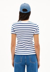 T-shirt rayé en blanc et bleu, avec un col rond et des manches courtes. Associé à un jean en denim bleu et une casquette bleu clair.