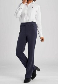 Marineblaue, hochtaillierte Hose mit elastischem Bund, kombiniert mit einem weißen Hemd mit Knöpfen. Die Hose zeichnet sich durch eine glatte Textur und ein weites Bein-Design aus.