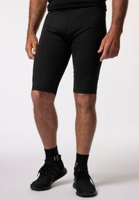 Shorts de sport noirs en tissu lisse et extensible avec une coupe ajustée, dotés d'une poche latérale et d'une longueur au-dessus du genou.