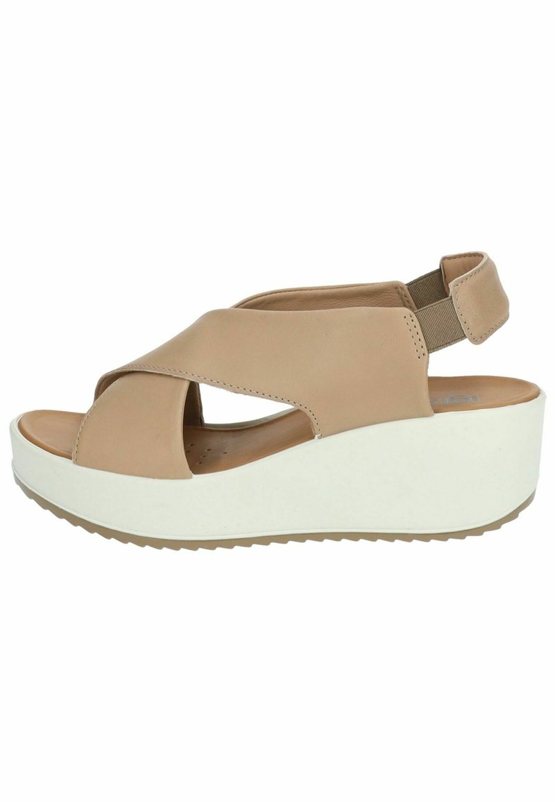 Sandalo wedge in pelle beige con design a strap incrociato, punta aperta e cinturino elasticizzato sul retro. Presenta una suola piatta bianca e fondo testurizzato.