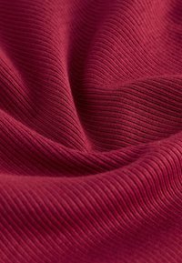 Burgundy ribbat tyg med texturerade linjer som visar fin elasticitet och mjukhet. Ytan är slät med en lätt glans.