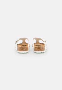 Kurken zolen sandalen met een lichtbeige band en witte accenten, voorzien van uitsnijdingen en verstelbare gouden gespen.