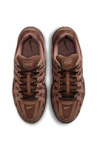 Ζεύγος καφέ αθλητικών παπουτσιών Nike με λεπτομέρειες από δίχτυ και δέρμα, μαύρα κορδόνια και εμφανή λογότυπα Nike στο εσωτερικό και στη γλώσσα, από άνωθεν θέα.