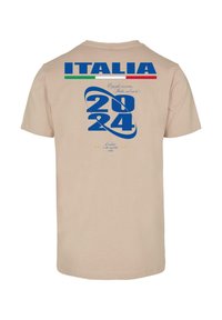 Beige pamut póló kék és zöld grafikával, melyen a "ITALIA", "2024" és dekoratív szöveg található. A dizájn csillagokat és absztrakt formákat is tartalmaz.