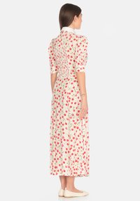 Abito midi floreale con maniche corte a sbuffo. Tessuto leggero con stampa di ciliegie rosse, dettaglio sul retro smock e colletto a punta.