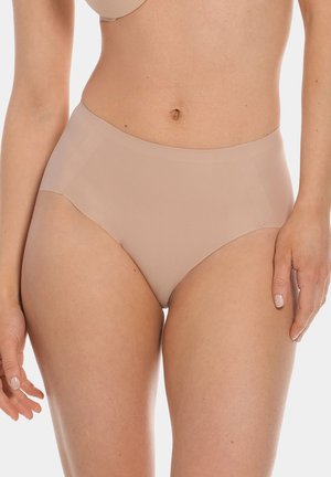 Vrouw die naadloos beige ondergoed met hoge taille en bijpassende bh draagt, staat met ontspannen handen langs haar lichaam tegen een witte achtergrond.