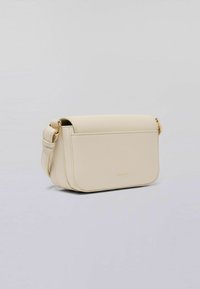 Kremowa torba crossbody wykonana z teksturowanego materiału syntetycznego. Posiada zapięcie na klapkę, złote elementy wykończenia oraz minimalistyczny design.