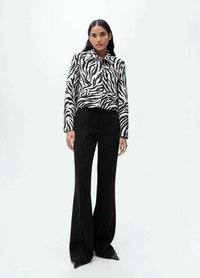 Zwart-wit gestreepte cropped jacket met een kraag, gecombineerd met hoge zwarte flairbroek en scherpe zwarte schoenen.