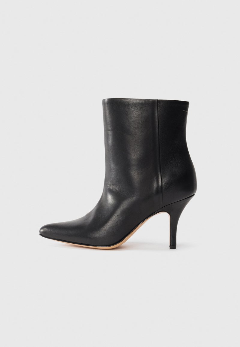 Črne usnjene gležnjarje s koničastim nosom, ozkim stiletto peto in gladko teksturo. Minimalističen dizajn brez vidnih kovinskih delov ali dekoracij.