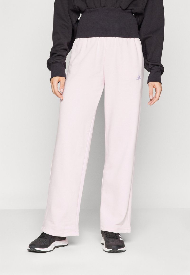 Pantalons de survêtement rose clair avec des jambes larges, fabriqués dans un matériau doux, dotés d'une taille élastique et de subtils accents de logo ton sur ton.