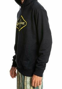 Sudadera negra con un logo amarillo, bolsillo frontal y capucha con cordón. Presenta puños y dobladillo acanalados, fabricada en un tejido suave.