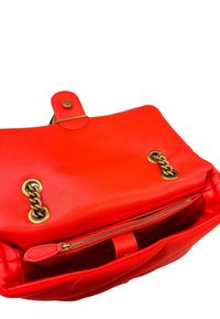 Borsa a mano rossa in pelle con una texture liscia, dotata di hardware dorato, chiusura a scatto e tasca interna con zip.