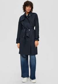 Granatowy płaszcz trench z paskiem, podwójnym zapięciem na guziki i kieszeniami bocznymi. Z klasycznym kołnierzem i teksturowanym materiałem.