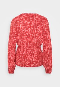 Blusa rossa con un delicato motivo a cuori bianchi, dotata di maniche lunghe, scollo rotondo e cintura elastica per un effetto arricciato.
