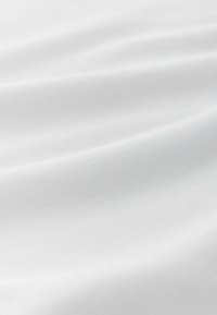 Bílá bavlněná látka s hladkou texturou, která má jemné záhyby a čistý, minimalistický design. Ideální pro různé textilní použití.