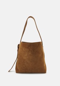 Sac à main en suède de couleur marron chaud. Il présente une seule longue bandoulière et une silhouette légèrement décontractée. Texture lisse avec des détails minimaux.