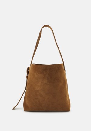 Borsa in suede di colore marrone caldo. Presenta una tracolla singola lunga e una silhouette leggermente morbida. Texture liscia con dettagli minimi.