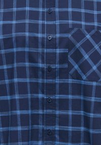 Marineblå rutete skjorte med horisontale og vertikale striper i lys blå, med brystlomme og seks svarte knapper foran.