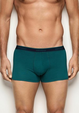 Boxer in cotone verde con elastico blu navy in vita, sul quale è stampato il marchio "yamamay" con lettere scure. Texture liscia, design aderente.