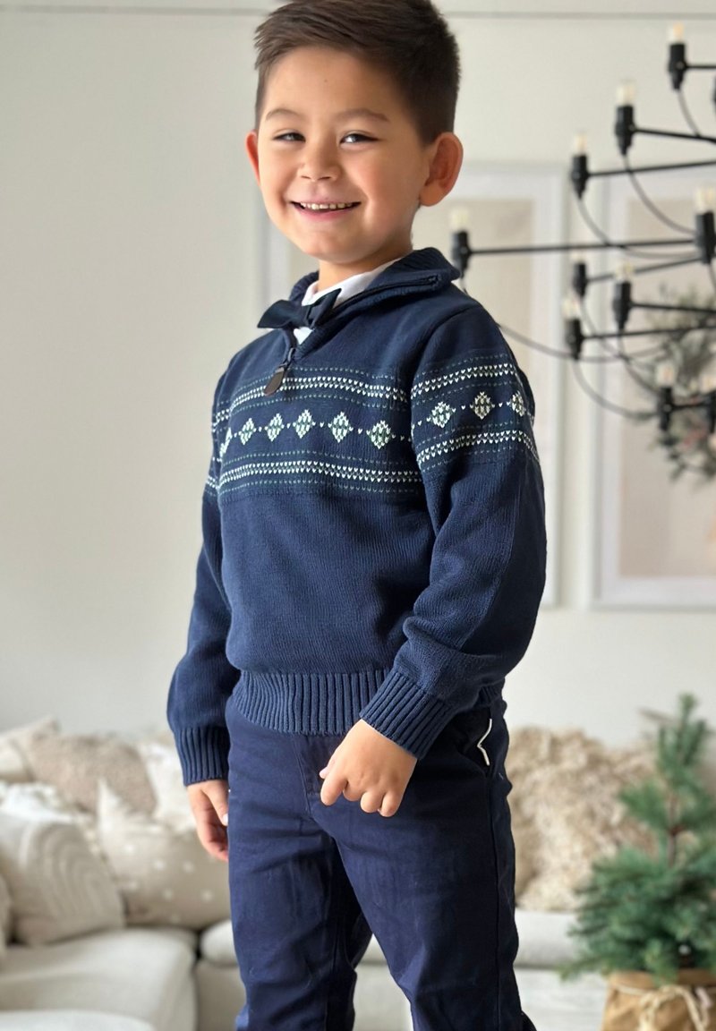 Navy sininen pörrösweater, jossa on kuvioitu muotoilu, joka sisältää vaaleansinisiä ja valkoisia timantteja, neulottu tekstuuri ja ribbireunat. Yhdistetty tummaan housuun.